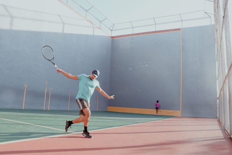 A padel player swinging a racket on an outdoor court