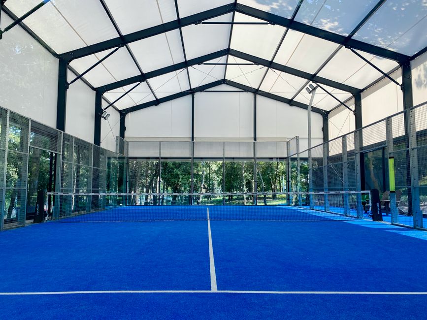 Modern indoor padel court with glass walls and blue surface